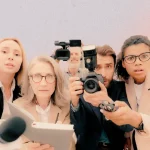 Fotografia de repórteres de diversas idades apontando câmeras e microfones para o interlocutor. Arte por Juliana Luiza e Clorofreela.
